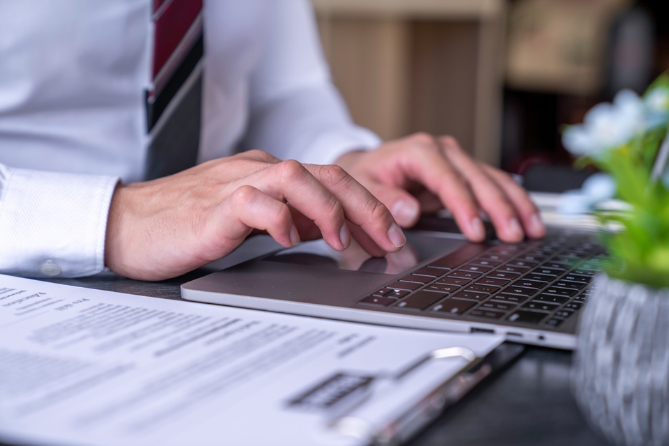 Elite Hotel Services - Hände eines Mannes, der an einem Schreibtisch am Laptop arbeitet